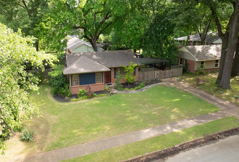 Brick exterior residence with a covered front porch and mature trees