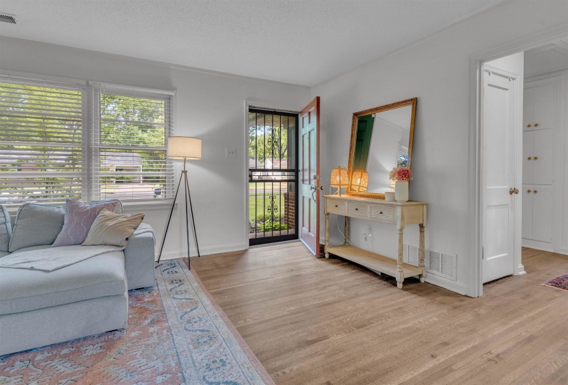 Entry foyer featuring wood-finish flooring, white walls, and a prominent front door with security screen