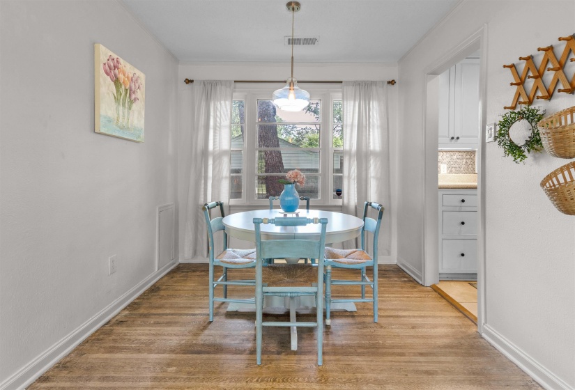 Dining area featuring wood-finish flooring, white baseboards, and a window with natural light