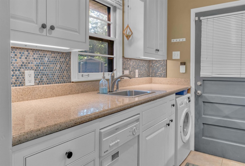 Kitchen area featuring light cabinetry, a stainless steel sink, a dishwasher, and a washer-dryer unit
