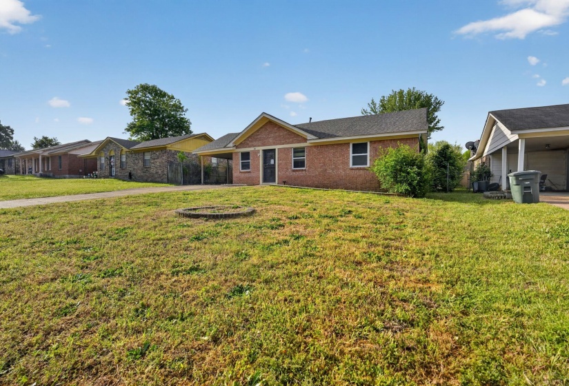 Brick exterior residence with a dark roof and a covered carport