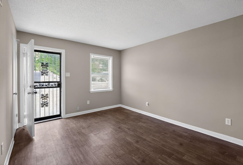 Spacious room featuring wood-finish flooring, neutral-toned walls, and white trim