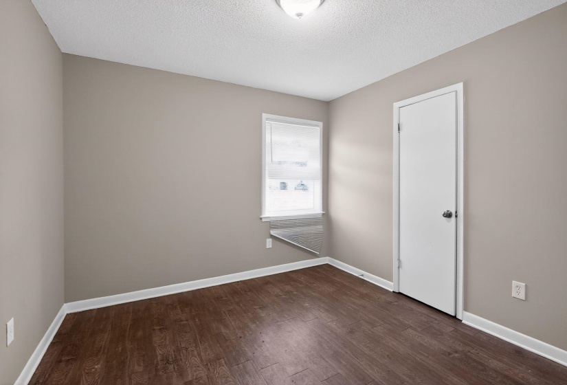 Room featuring wood-finish flooring, neutral wall paint, and white trim