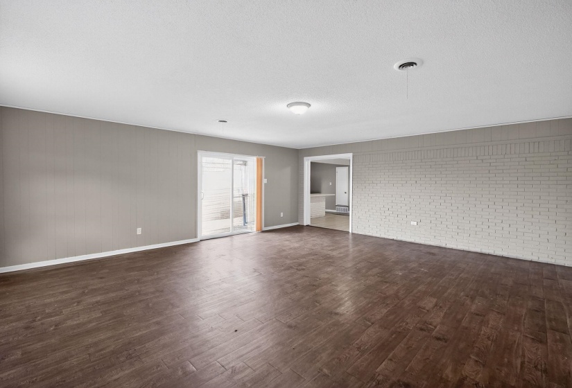 Expansive interior space featuring wood-finish flooring, light gray painted walls, and a white brick accent wall