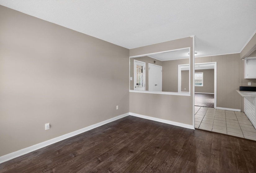 Interior space featuring wood-finish flooring, neutral wall tones, white trim, and a pass-through window opening