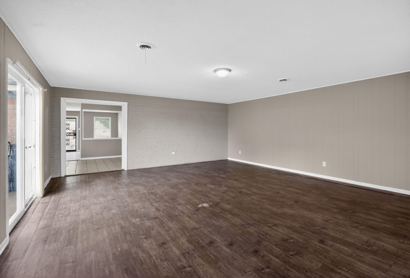 Spacious room featuring wood-finish flooring, white baseboards, and a neutral wall palette