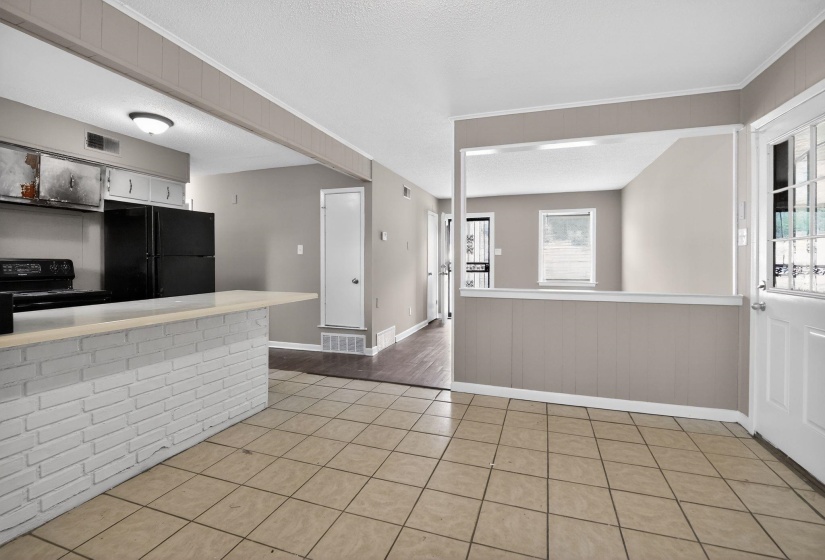 Kitchen area with a white brick-finish breakfast bar, black appliances, and neutral wall paint