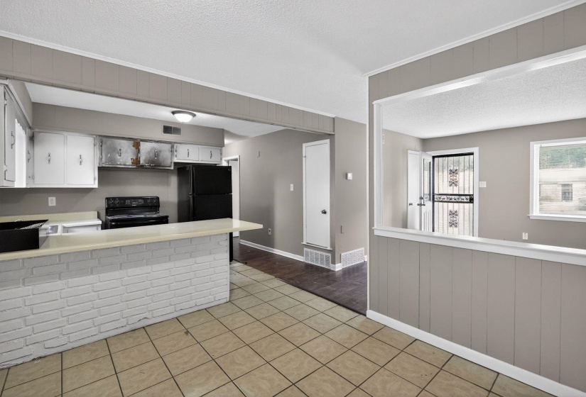 Kitchen area featuring a breakfast bar with a white brick base, light-toned countertop, and white cabinetry