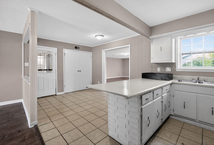 Kitchen area featuring an eat-at peninsula with a white brick base, white cabinetry, and a double basin sink