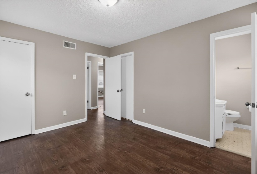 Spacious room featuring wood-finish flooring, neutral paint tones, white trim, and a ceiling-mounted light fixture