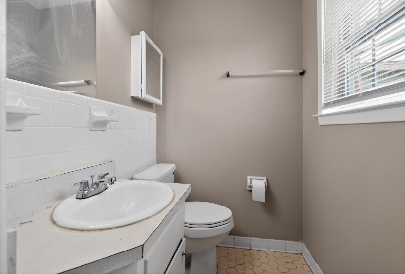 Bathroom featuring a vanity with an integrated sink, chrome faucet, and white tile backsplash