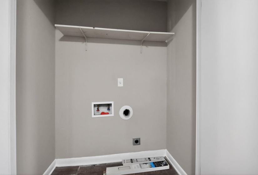 Dedicated laundry closet featuring a wall-mounted shelf, utility hookups, and wood-finish flooring