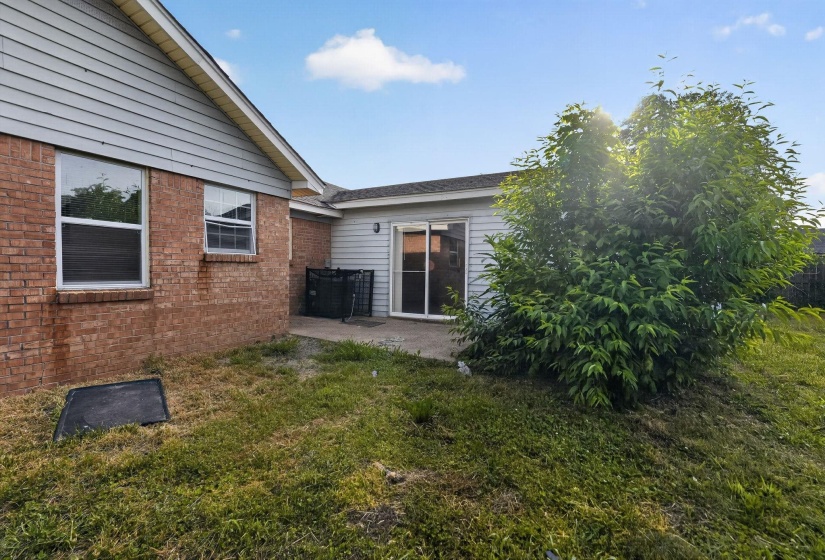 Exterior brick and siding elevation featuring multiple windows and a sliding glass door