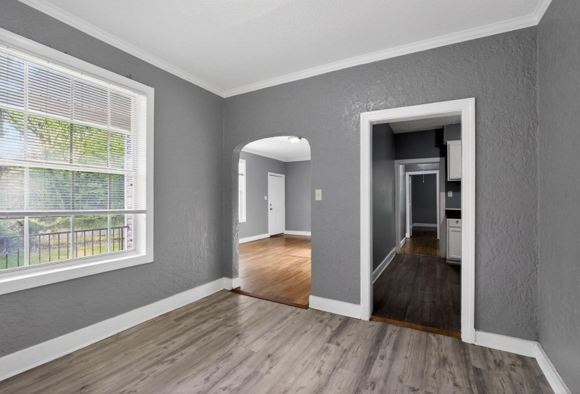 Interior featuring light gray wood-finish flooring, textured gray walls, and white trim