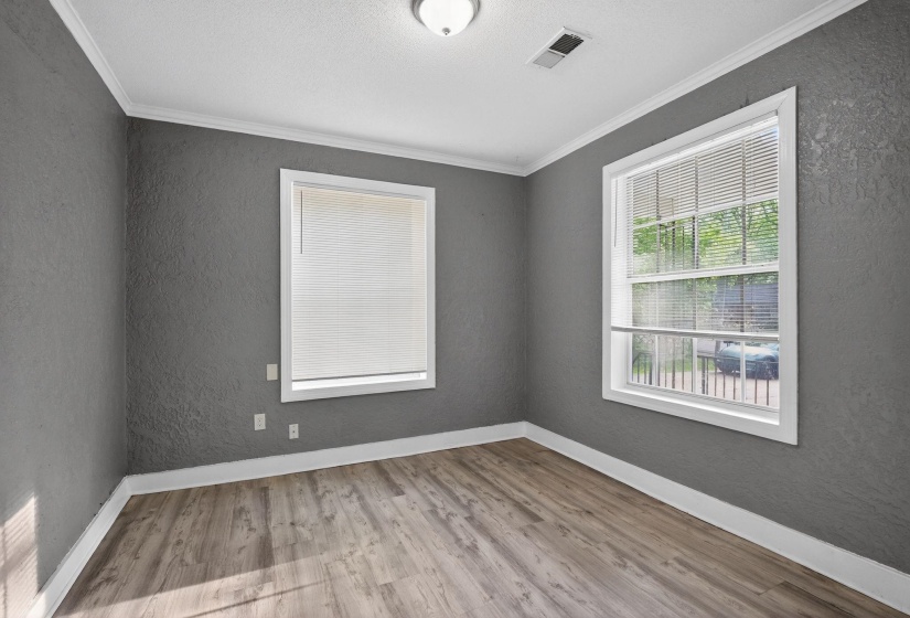 Room featuring wood-finish flooring, textured walls, white trim, and a ceiling-mounted light fixture