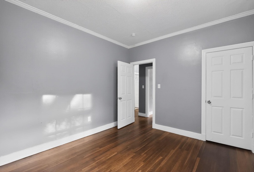Interior room featuring wood-finish flooring, light gray walls, and white crown molding