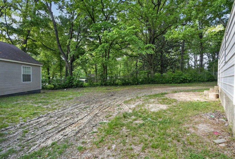 Expansive outdoor area featuring mature trees and a perimeter fence