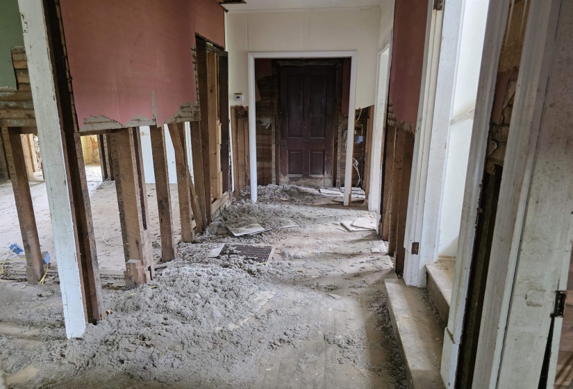 Interior framing exposed, featuring existing wood flooring and partial wall coverings