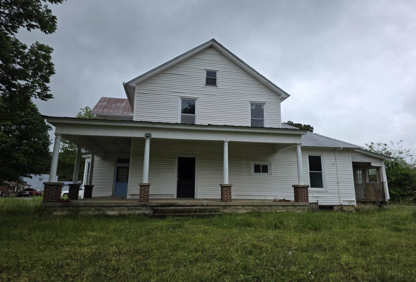 Two-story white siding exterior featuring a full-width covered porch with multiple support columns