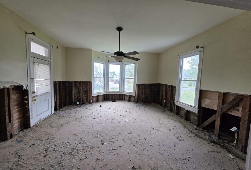 Room featuring a bay window, ceiling fan with integrated lighting, and multiple windows