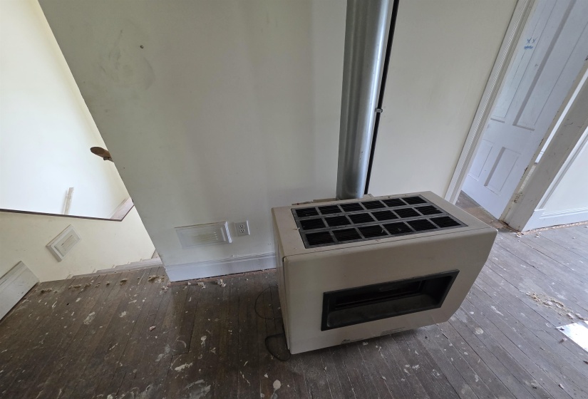 Freestanding stove with a metal flue, positioned on wood-finish flooring