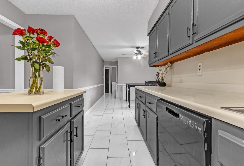 Kitchen featuring gray cabinetry, light countertops, and a built-in black dishwasher
