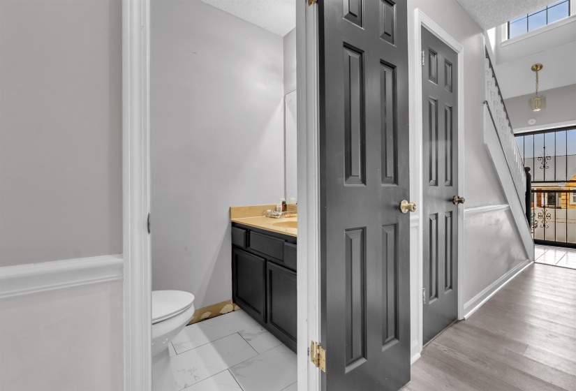 Powder room with a dark wood-finish vanity, light-toned countertop, and white tile flooring