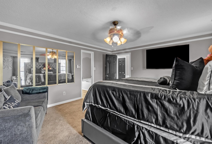 Spacious interior featuring a neutral wall color, crown molding, and carpet flooring