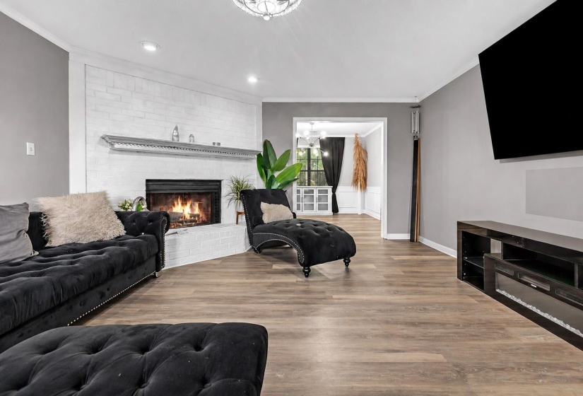 Living area featuring a white painted brick fireplace with a dark metal mantel, wood-finish flooring, and recessed lighting