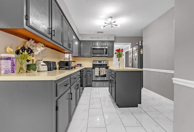 Kitchen featuring gray cabinetry, light-toned countertops, and stainless steel appliances