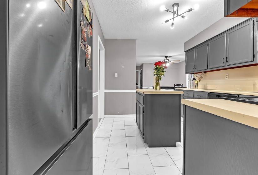 Kitchen featuring wood-finish countertops, dark cabinetry, and white tile flooring
