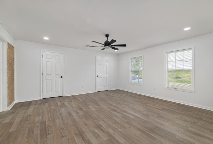 Spacious interior room featuring wood-finish flooring, two paneled doors, and two windows