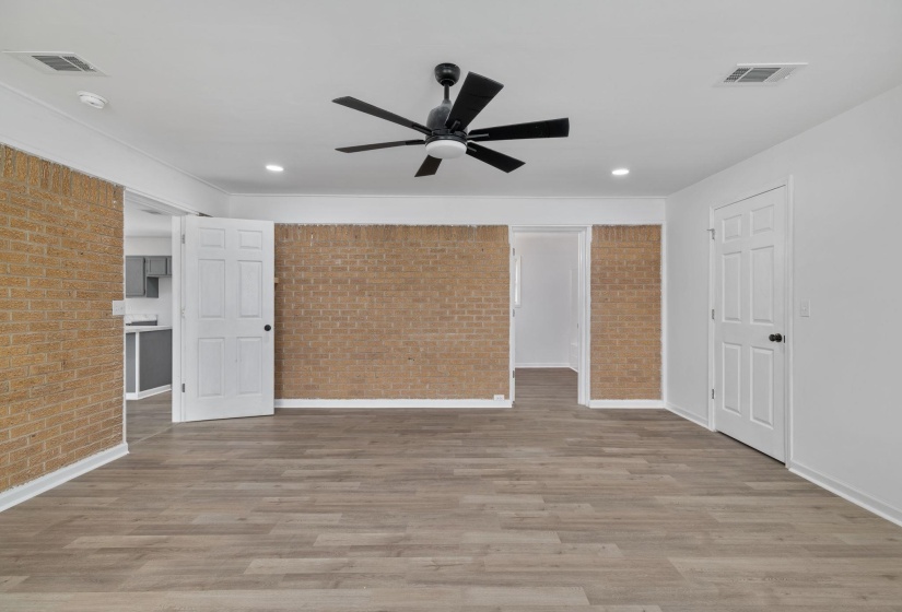 Spacious interior featuring wood-finish flooring, exposed brick wall accents, and recessed lighting