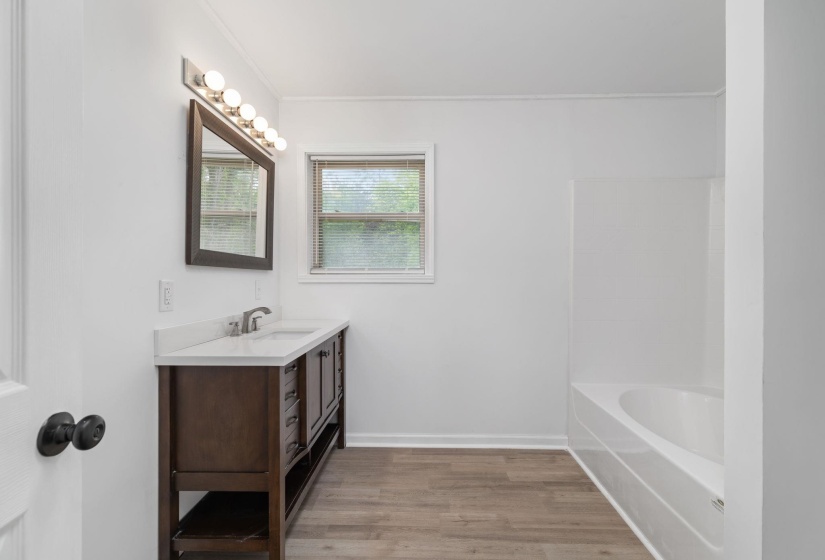 Bathroom featuring a dark wood-finish vanity with a white countertop and undermount sink, a large framed mirror, and a five-light vanity fixture