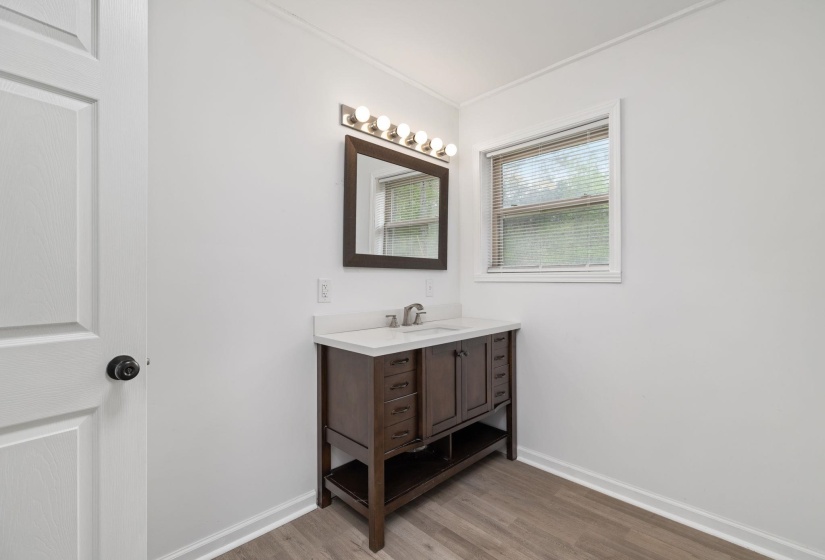Bathroom featuring a dark wood-finish vanity with an integrated sink and white countertop