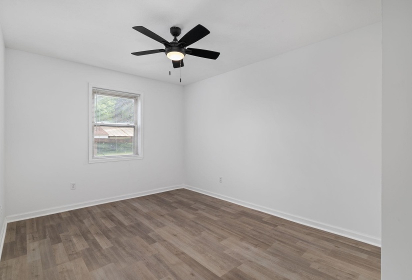 Room featuring wood-finish flooring, white walls, and a window with white trim