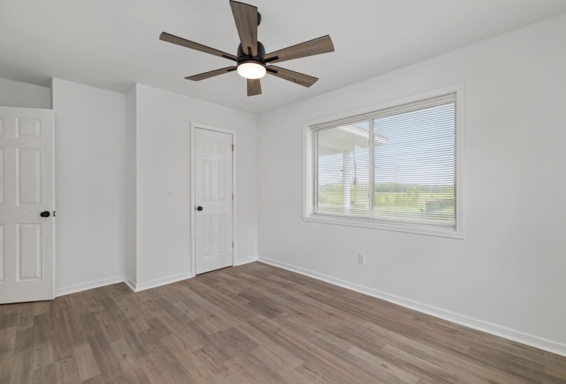 Bright interior space featuring wood-finish flooring, crisp white walls, and a contemporary ceiling fan