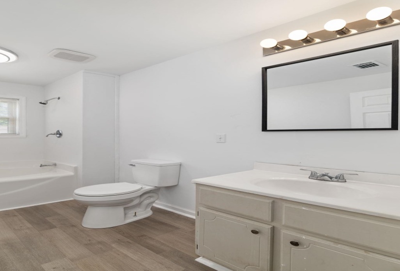 Bathroom featuring a white vanity with integrated sink, chrome faucet, and rectangular mirror with a four-bulb vanity light