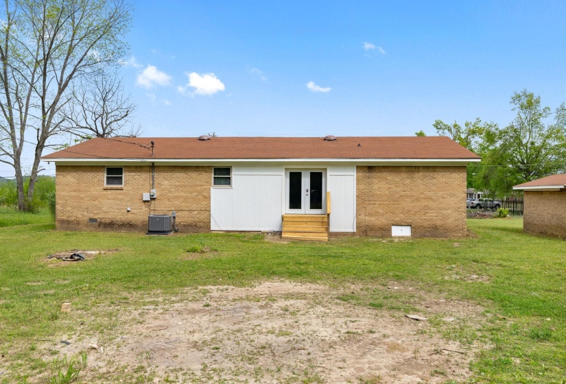 Rear exterior featuring brick and white siding, dual pane windows, a brown shingle roof, and an exterior AC unit