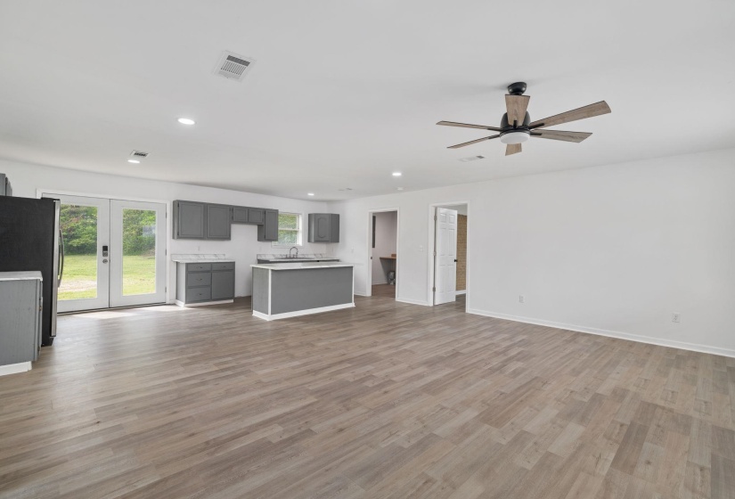 Open-concept living area featuring wood-finish flooring, a contemporary ceiling fan, recessed lighting, and a kitchen with gray cabinetry, white countertops, and a central island