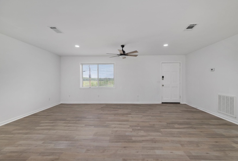 Spacious room featuring wood-finish flooring, white walls, and recessed lighting