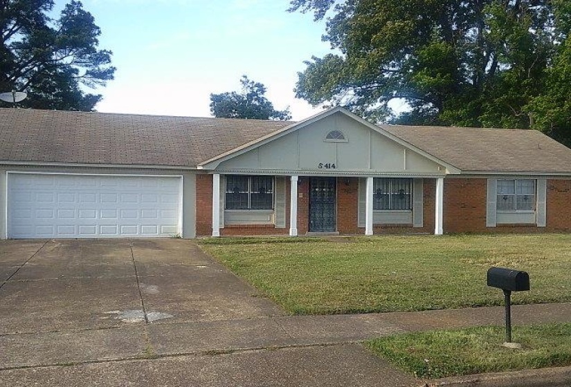 Brick exterior ranch home with an attached two-car garage, concrete driveway, and front lawn