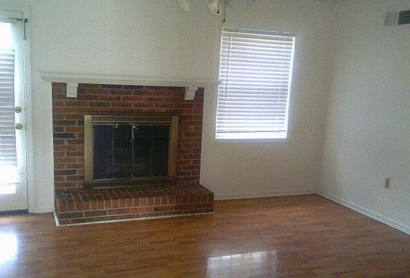 Brick fireplace with a white mantle, glass doors, and a raised hearth