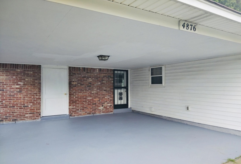 Covered carport featuring a painted concrete floor
