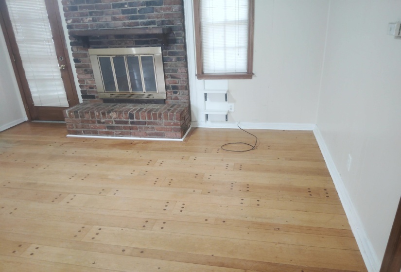 Brick fireplace with a metal insert and hearth, complemented by a light wood-finish flooring