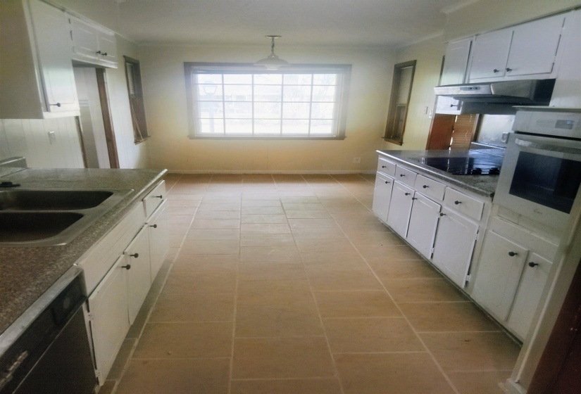 Kitchen featuring white cabinetry with dark hardware, granite-look countertops, and tile flooring