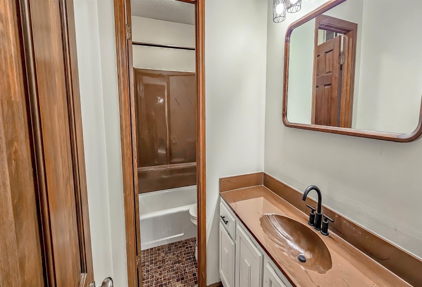 Bathroom vanity with integrated brown basin, matte black faucet, and white cabinetry
