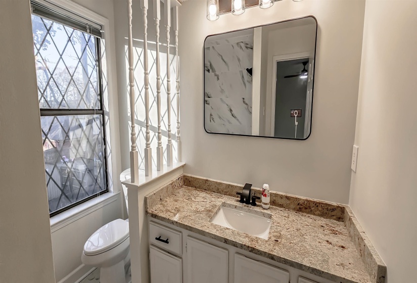 Bathroom vanity with a granite countertop, undermount sink, and matte black hardware