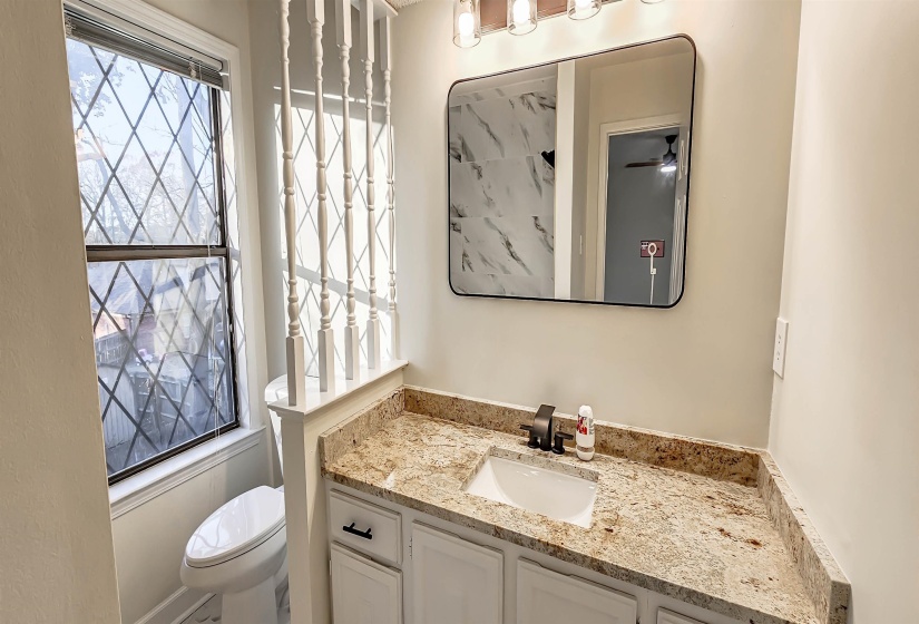 Bathroom vanity featuring a light granite countertop, undermount sink, and dark bronze faucet