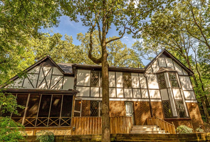 Tudor-style residence featuring a brick and half-timbered facade, diamond-pane windows, and a screened porch